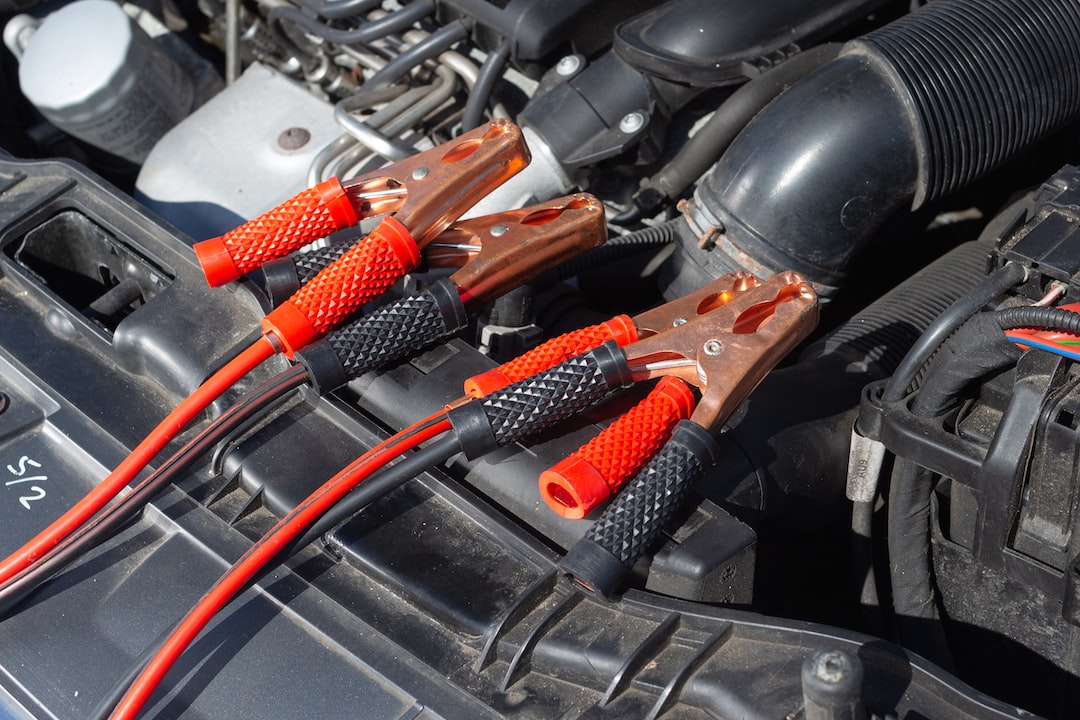 **Title:** Car Engine Bay with Jumper Cables

**Alt Text:** Car engine bay showing radiator support and air-intake hoses with red and black jumper cables for jump-starting